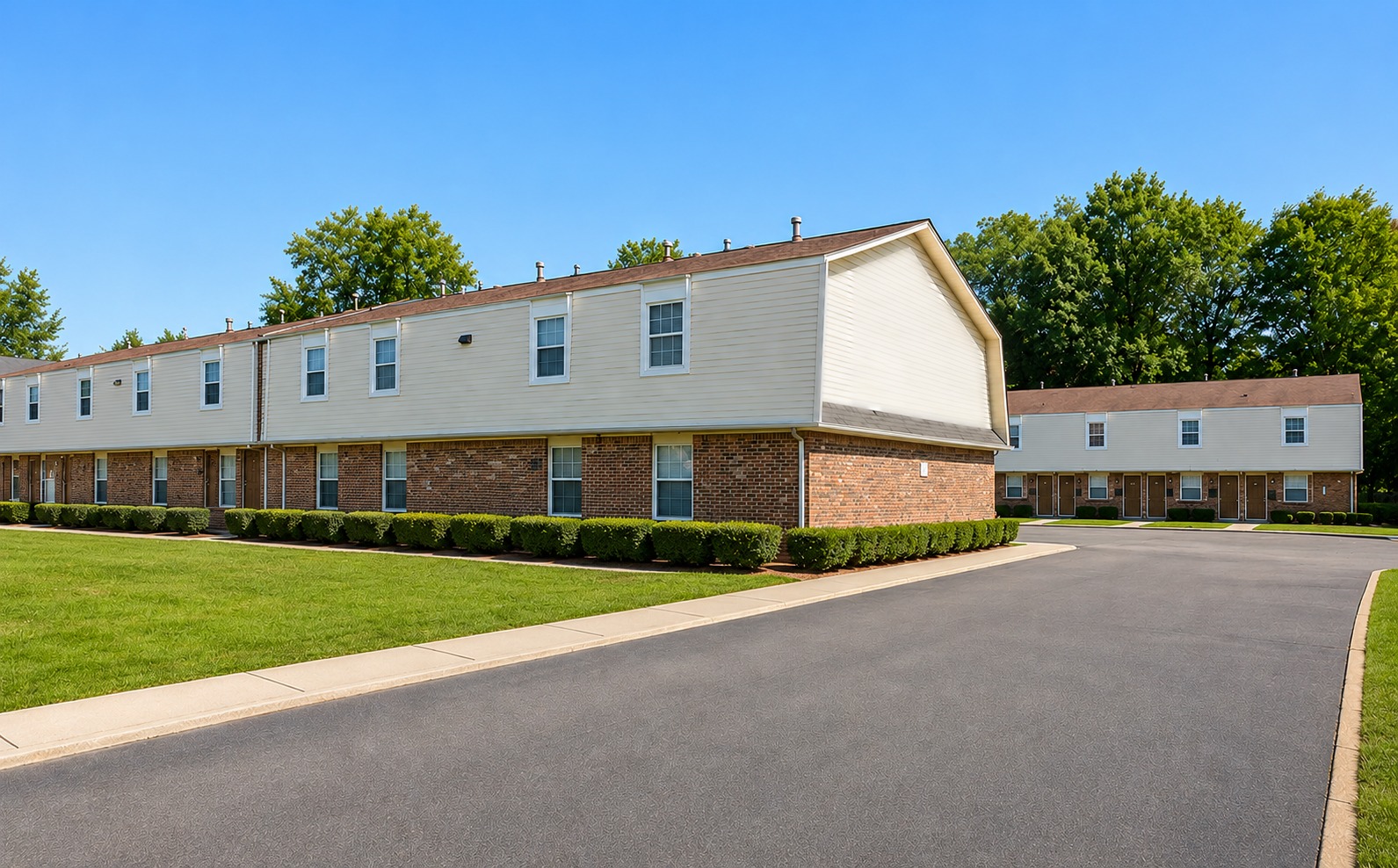 Red Oak Apartments exterior courtyard with brick buildings, lawn, and clear blue sky